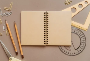 Open spiral notebook with office supplies on desk